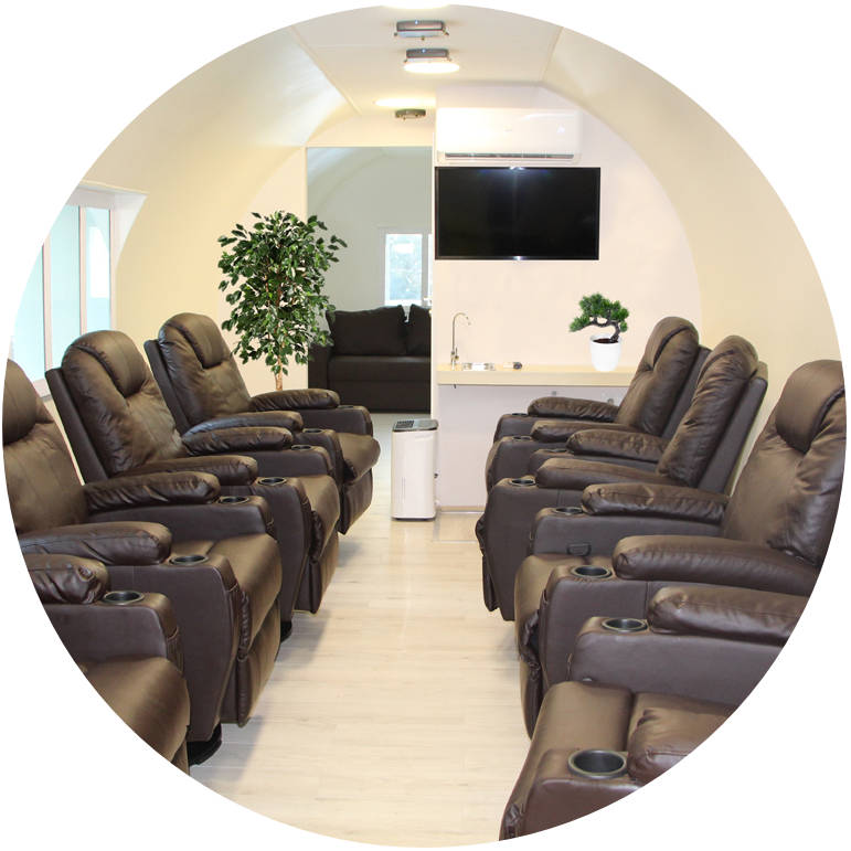 Wnętrze komory normobarycznej — wygodne fotele skórzane, telewizor i drzewko bonsai